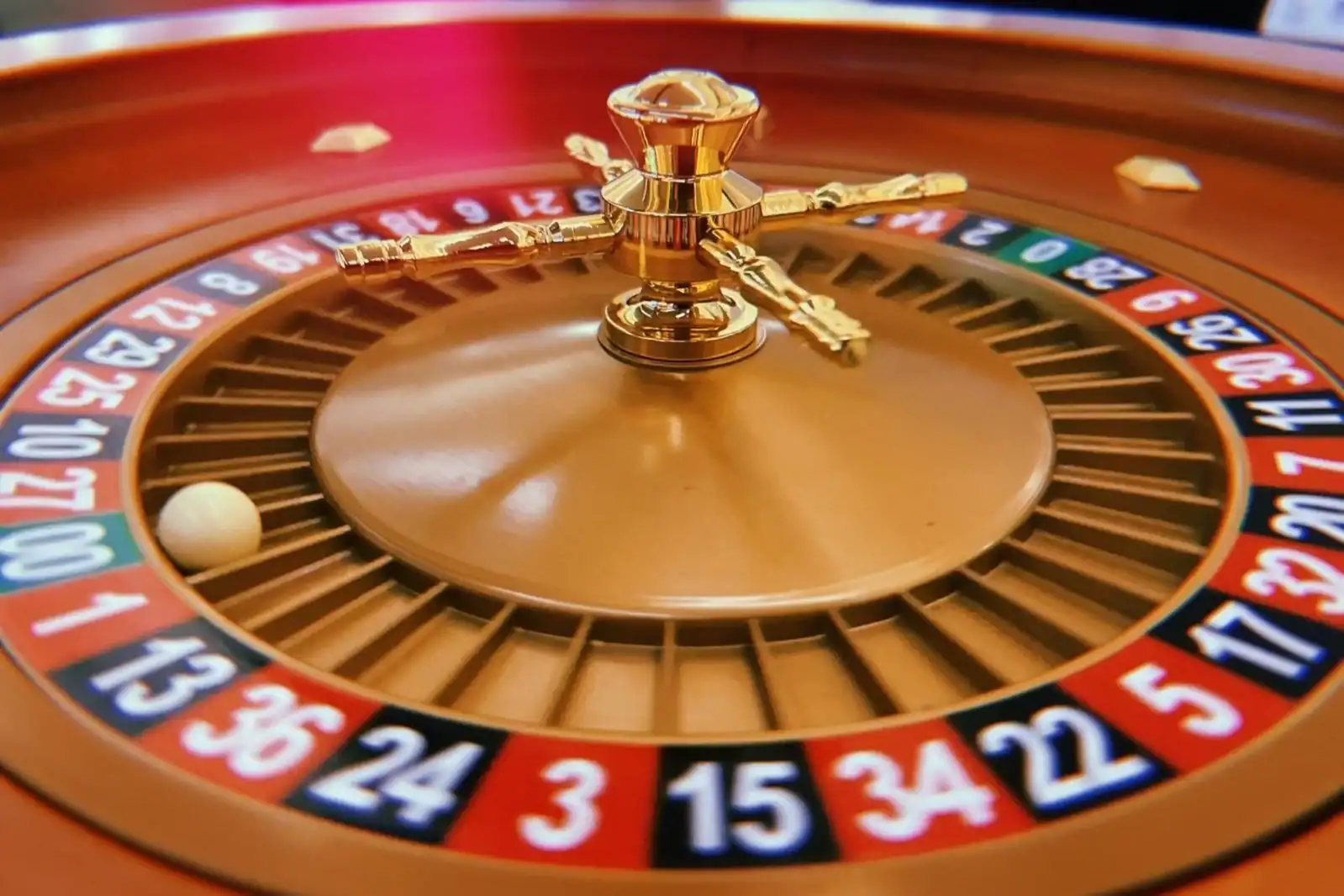 Close-up of a roulette wheel with a white ball and gold details.